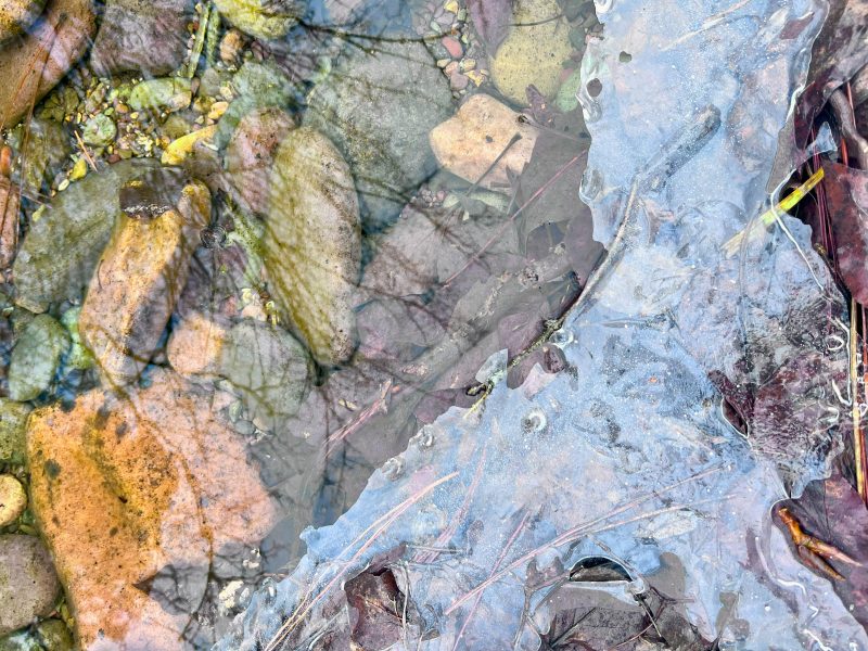 close-up photo of some rocks. It features a view of the bedrock with ice on the part of surface. The rocks are part of a natural outdoor setting.